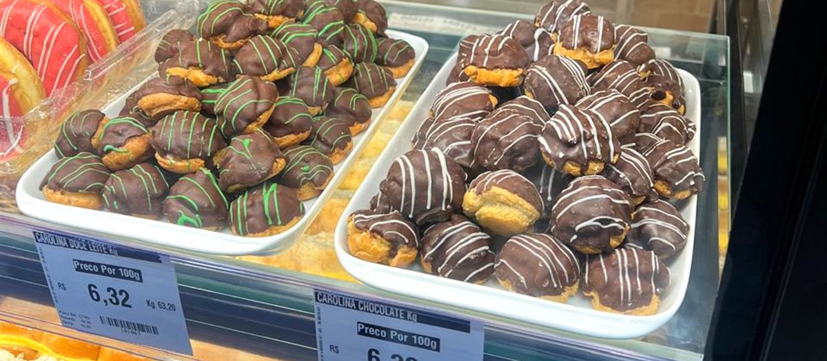 Bandejas de Carolinas de doce de leite e chocolate em vitrine de padaria